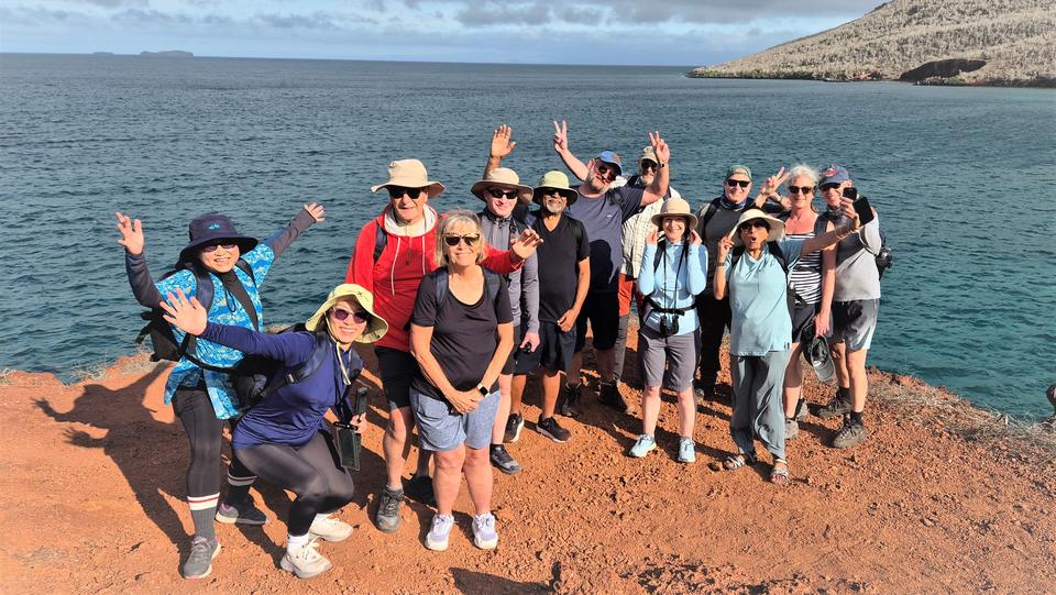 Group of travelers waving on red sand by the sea