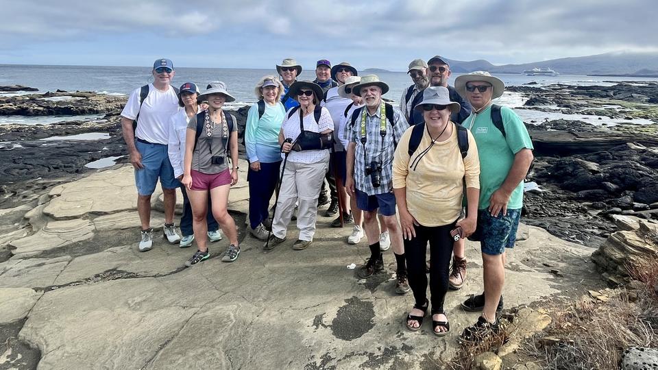 Group of travelers on volcanic rocks by the sea