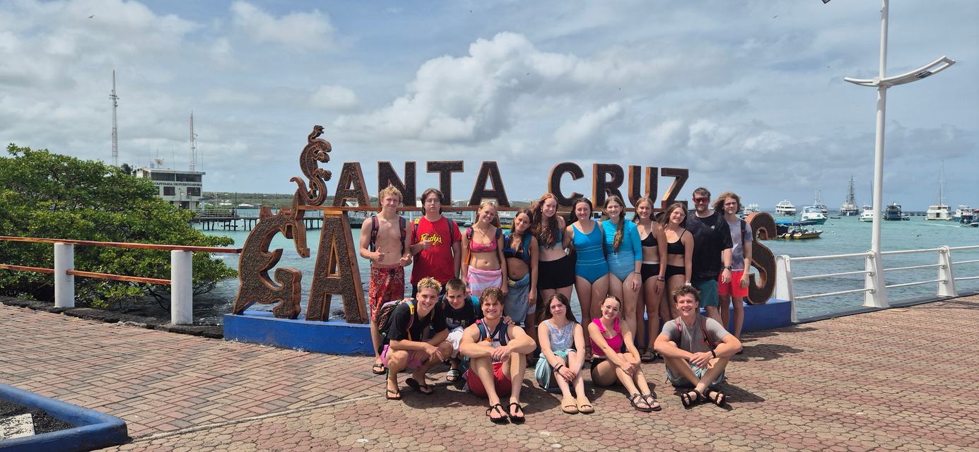 Group of travelers in front of the Santa Cruz sign at the Puerto Ayora pier