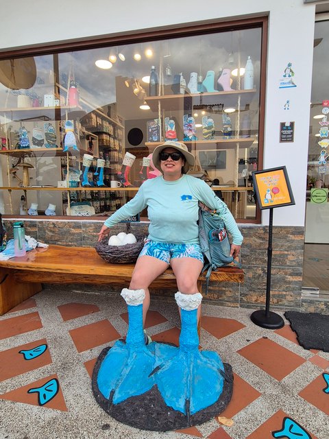 Traveler posing with a sculpture of a blue-footed booby's feet