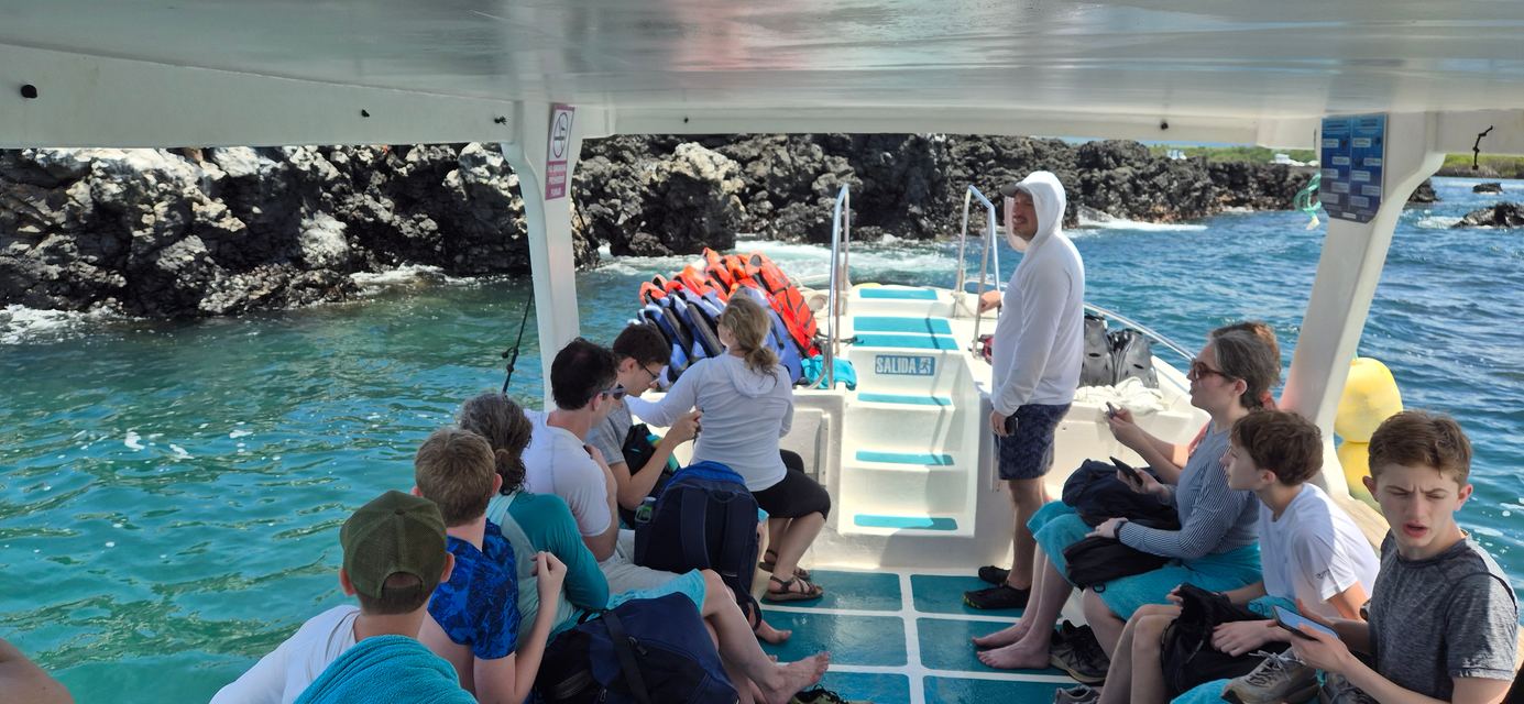 Travelers aboard a tour boat along a lava coastline