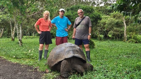 Three travelers next to a giant tortoise in the Santa Cruz highlands